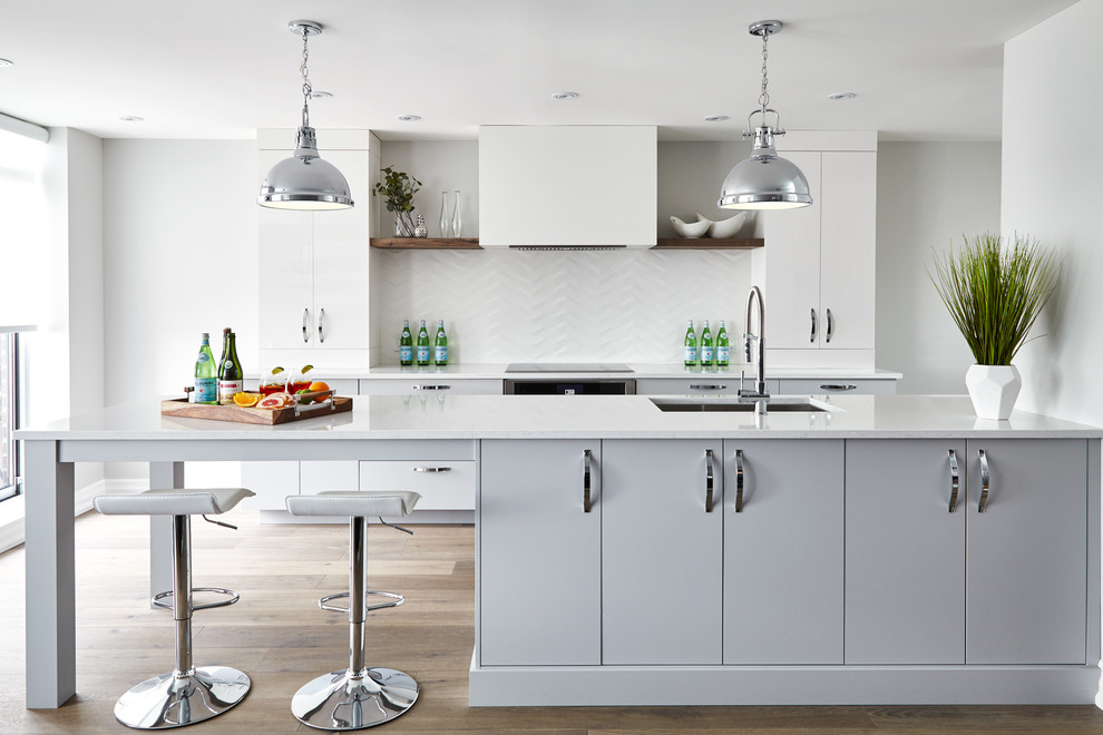 Foto di una cucina contemporanea con lavello sottopiano, ante lisce, ante grigie, paraspruzzi bianco, pavimento in legno massello medio e pavimento marrone