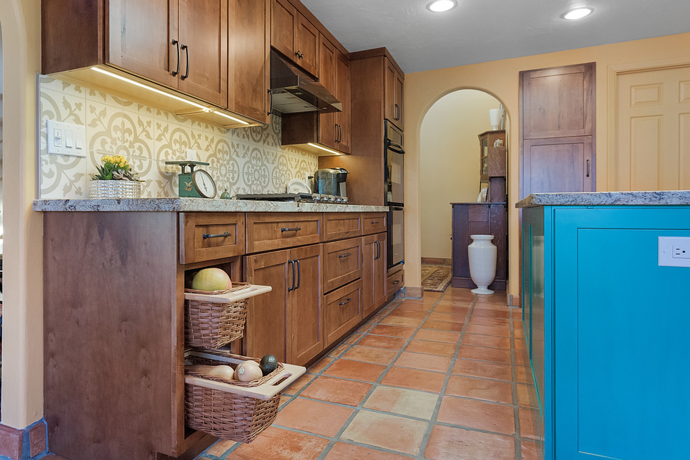 Foto på ett mellanstort vintage beige kök, med en nedsänkt diskho, släta luckor, bruna skåp, granitbänkskiva, beige stänkskydd, stänkskydd i porslinskakel, svarta vitvaror, klinkergolv i terrakotta, en köksö och rött golv