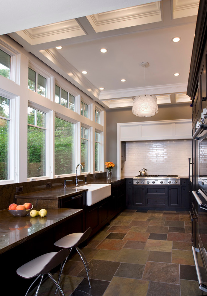 Exempel på ett klassiskt kök, med en rustik diskho, luckor med infälld panel, skåp i mörkt trä, granitbänkskiva, brunt stänkskydd, stänkskydd i glaskakel och integrerade vitvaror