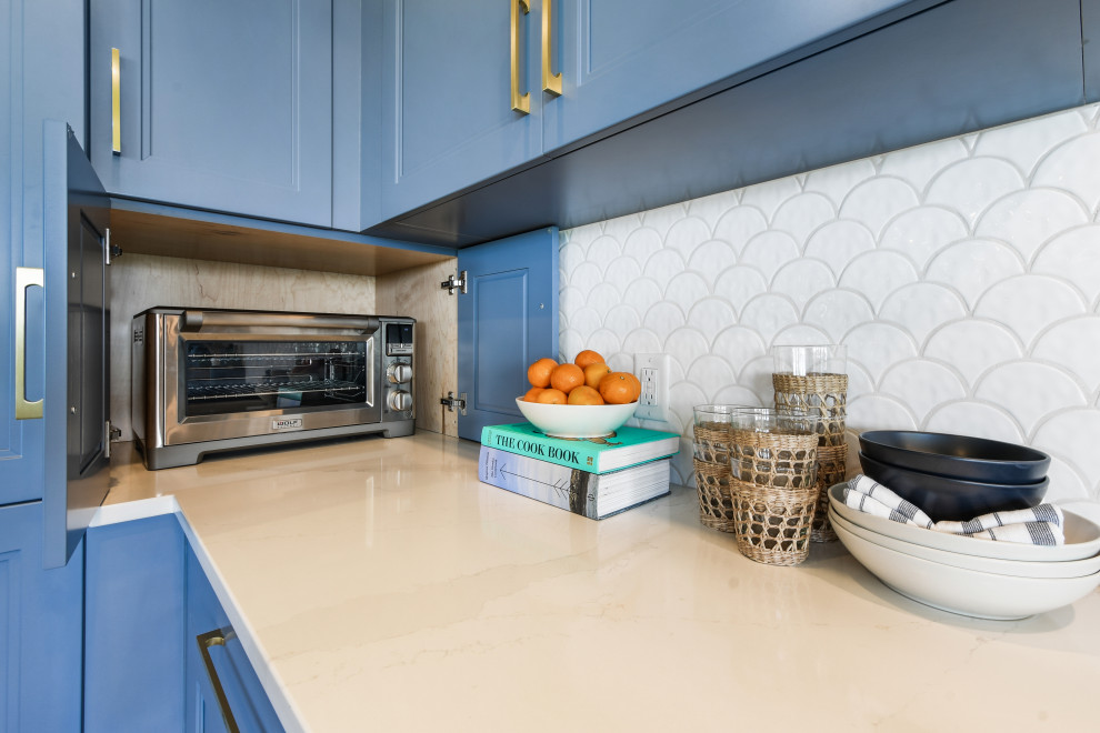 Mid-sized beach style l-shaped porcelain tile, brown floor and shiplap ceiling open concept kitchen photo in Other with a farmhouse sink, shaker cabinets, blue cabinets, quartz countertops, white backsplash, porcelain backsplash, black appliances, an island and white countertops