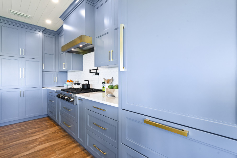 Design ideas for a medium sized coastal l-shaped open plan kitchen in Other with a belfast sink, shaker cabinets, blue cabinets, engineered stone countertops, white splashback, porcelain splashback, black appliances, porcelain flooring, an island, brown floors, white worktops and a timber clad ceiling.