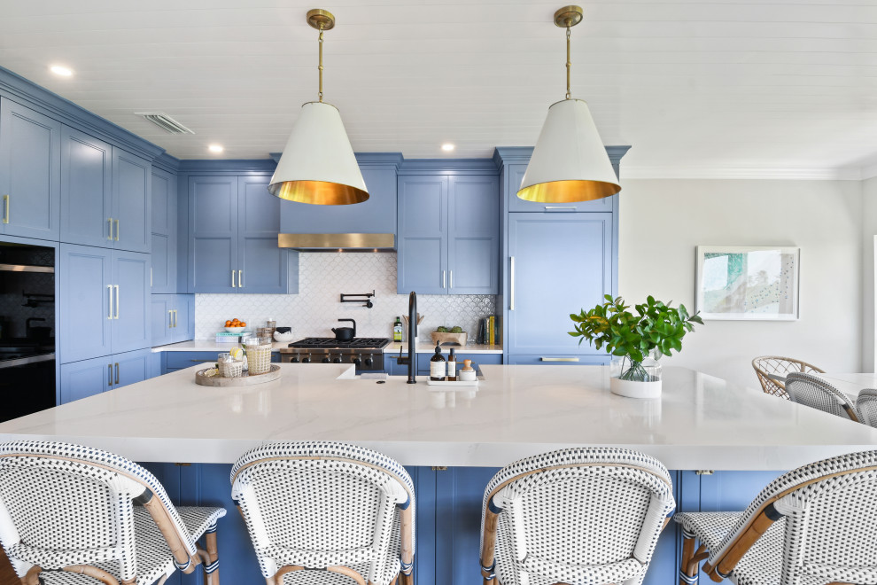 Mid-sized beach style l-shaped porcelain tile, brown floor and shiplap ceiling open concept kitchen photo in Other with a farmhouse sink, shaker cabinets, blue cabinets, quartz countertops, white backsplash, porcelain backsplash, black appliances, an island and white countertops