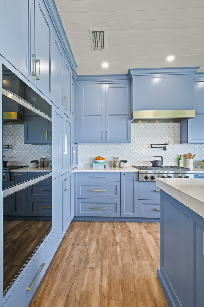 Design ideas for a medium sized nautical l-shaped open plan kitchen in Other with a belfast sink, shaker cabinets, blue cabinets, engineered stone countertops, white splashback, porcelain splashback, black appliances, porcelain flooring, an island, brown floors, white worktops and a timber clad ceiling.