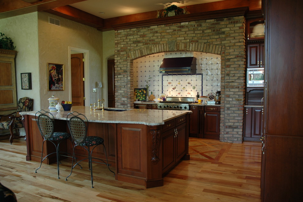 Пример оригинального дизайна: п-образная кухня в классическом стиле с врезной мойкой, фасадами с выступающей филенкой, темными деревянными фасадами, гранитной столешницей и техникой под мебельный фасад