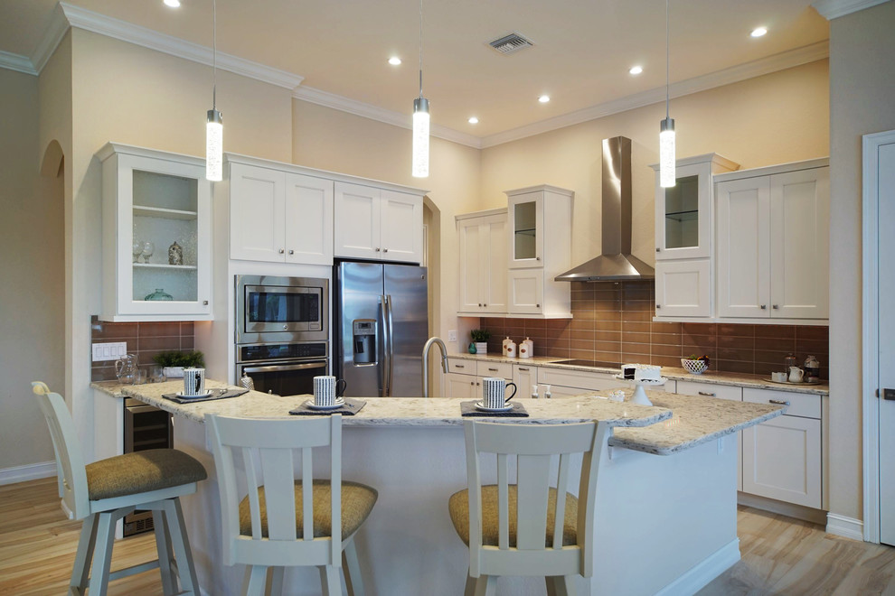 Inspiration for a mid-sized transitional l-shaped porcelain tile and beige floor open concept kitchen remodel in Miami with an undermount sink, shaker cabinets, white cabinets, granite countertops, brown backsplash, glass tile backsplash, stainless steel appliances, an island and beige countertops