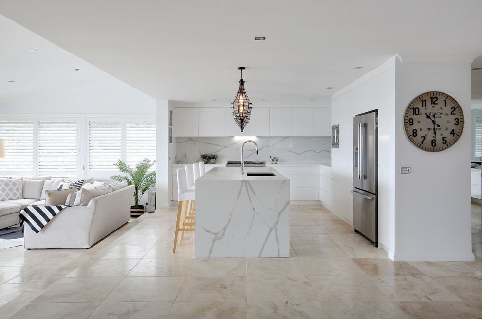 Cette image montre une cuisine américaine design avec un plan de travail en quartz modifié, une crédence blanche, une crédence en dalle de pierre, îlot et un plan de travail blanc.