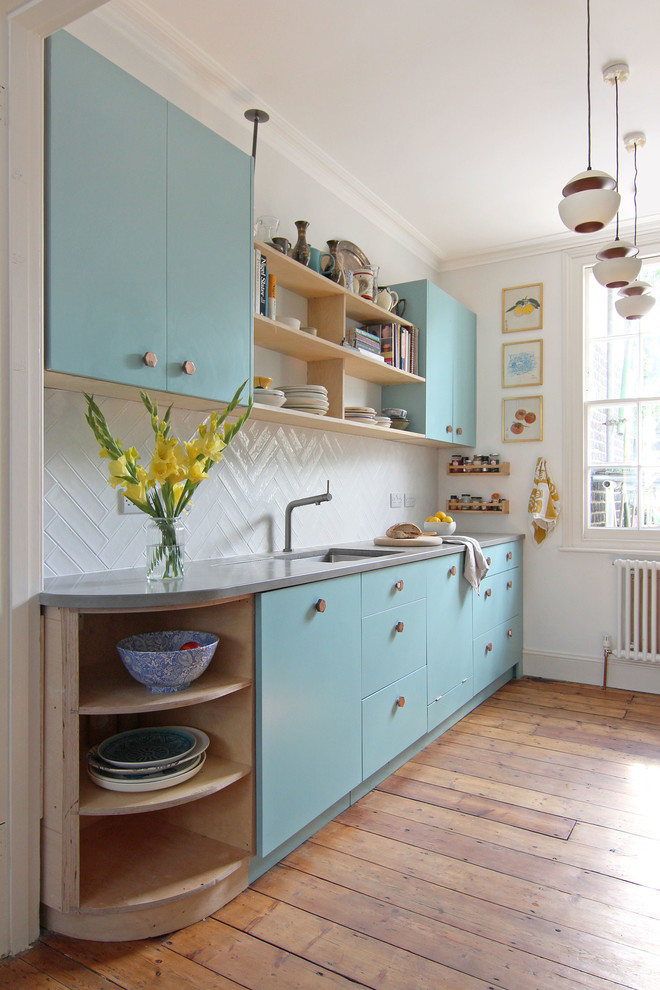 Einzeilige, Kleine Nordische Küche mit Unterbauwaschbecken, flächenbündigen Schrankfronten, blauen Schränken, Küchenrückwand in Weiß, braunem Holzboden und Betonarbeitsplatte in London