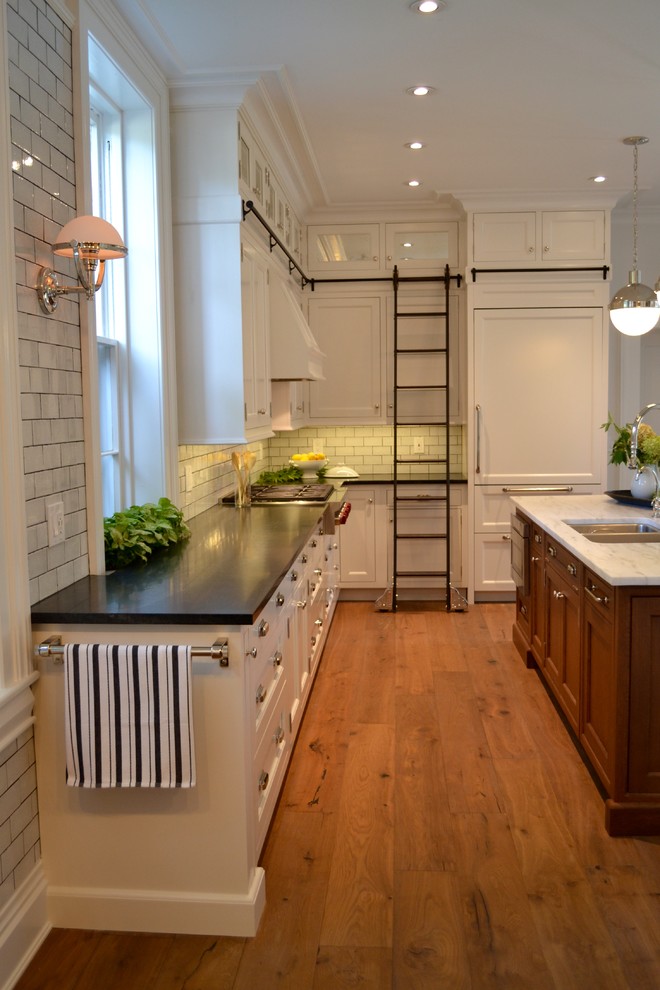 Inspiration for a medium sized traditional kitchen in Boston with a submerged sink, recessed-panel cabinets, white cabinets, composite countertops, white splashback, metro tiled splashback, integrated appliances, medium hardwood flooring and an island.