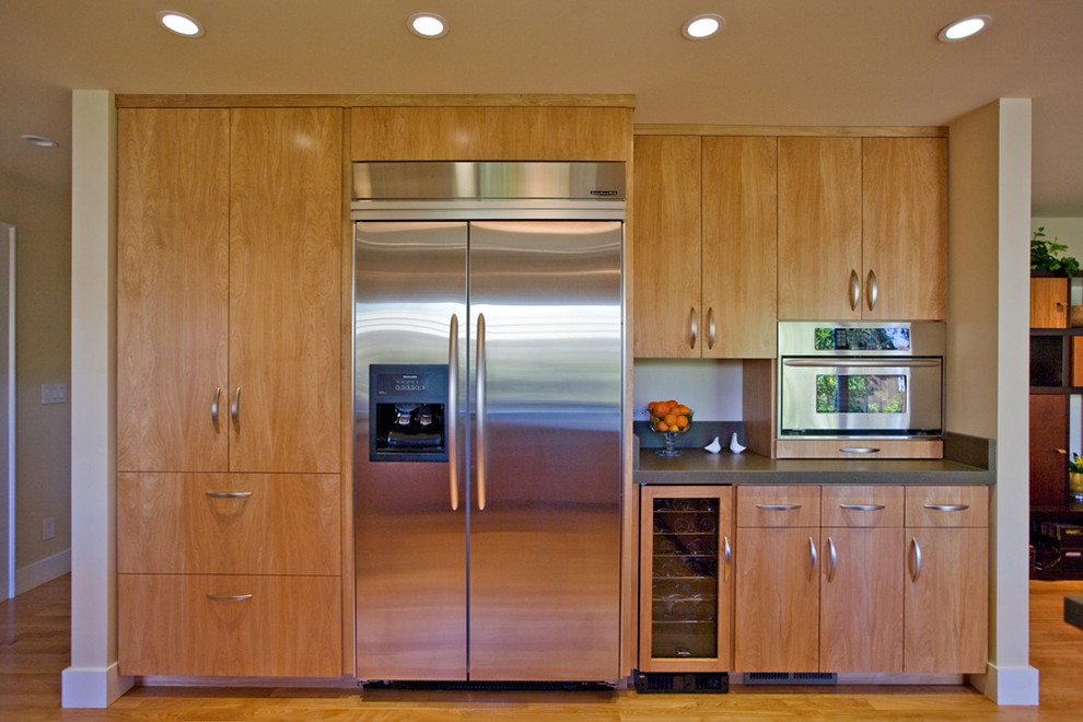 Exemple d'une cuisine ouverte moderne en U et bois clair de taille moyenne avec un évier encastré, un placard à porte plane, un plan de travail en béton, une crédence grise, un électroménager en acier inoxydable, une crédence en carreau de ciment et un sol en bois brun.