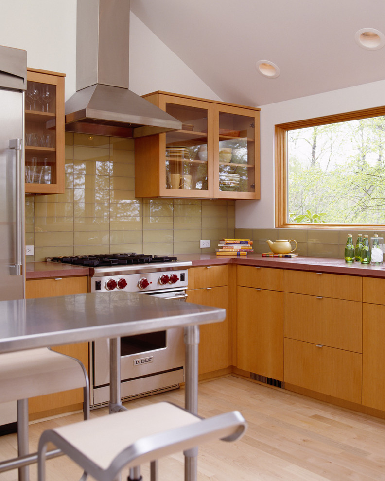 Minimalist l-shaped kitchen photo in Portland with glass-front cabinets, medium tone wood cabinets, concrete countertops, yellow backsplash, glass tile backsplash and stainless steel appliances