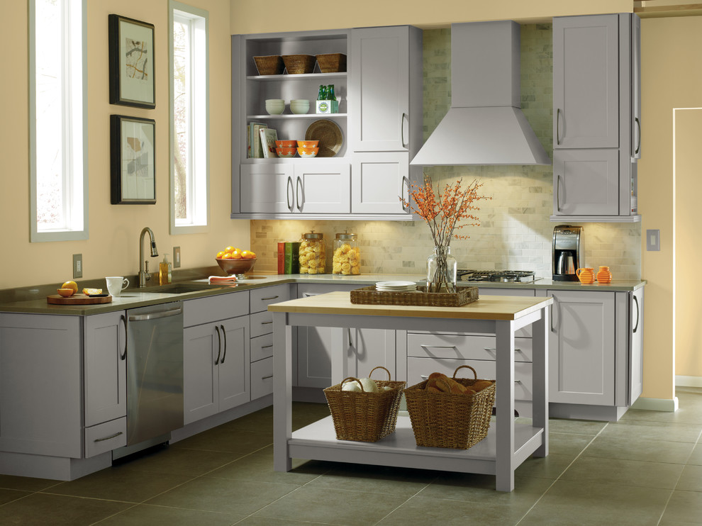 Bild på ett mellanstort funkis l-kök, med en undermonterad diskho, luckor med infälld panel, grå skåp, granitbänkskiva, grått stänkskydd, stänkskydd i stickkakel, rostfria vitvaror, klinkergolv i keramik och en köksö