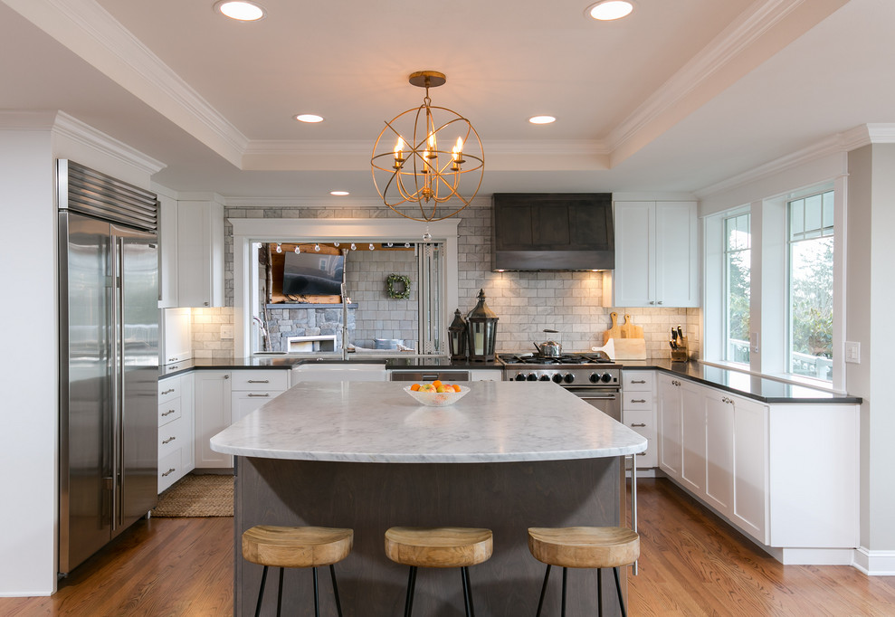 Kitchen - transitional u-shaped medium tone wood floor and brown floor kitchen idea in Seattle with a farmhouse sink, shaker cabinets, white cabinets, marble countertops, gray backsplash, subway tile backsplash, stainless steel appliances, an island and gray countertops