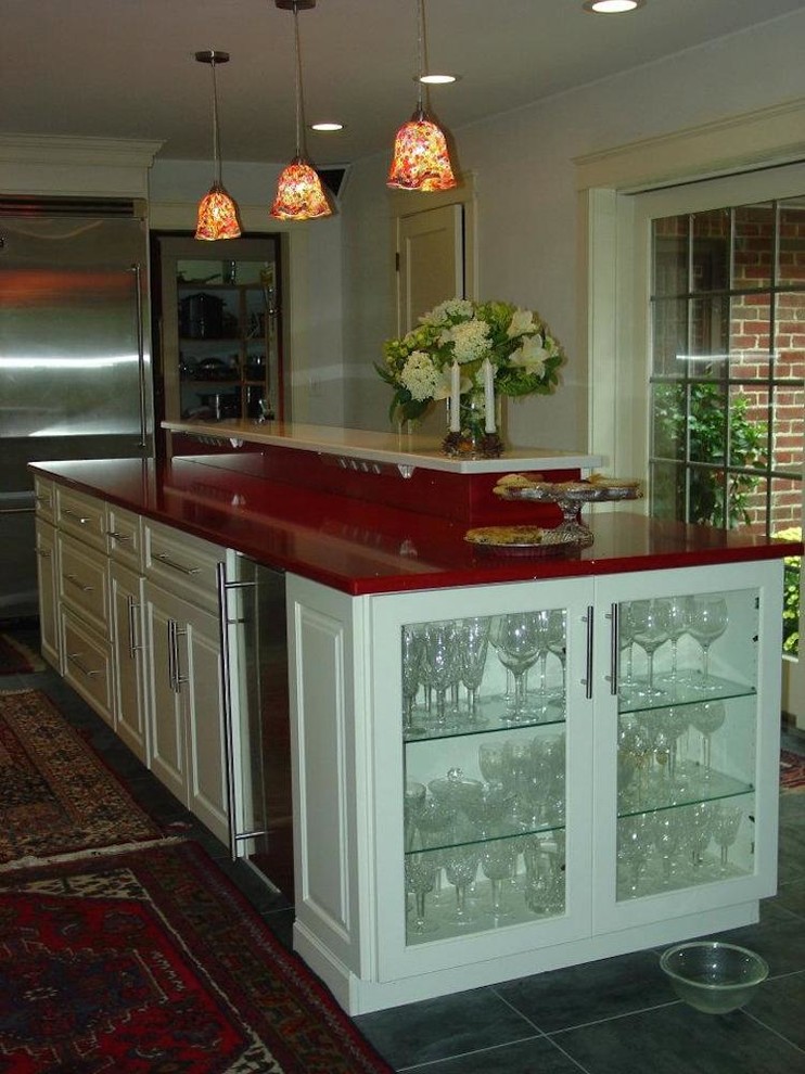 Foto på ett mellanstort vintage röd kök, med en undermonterad diskho, luckor med upphöjd panel, vita skåp, bänkskiva i kvarts, svart stänkskydd, stänkskydd i mosaik, rostfria vitvaror, skiffergolv och en köksö