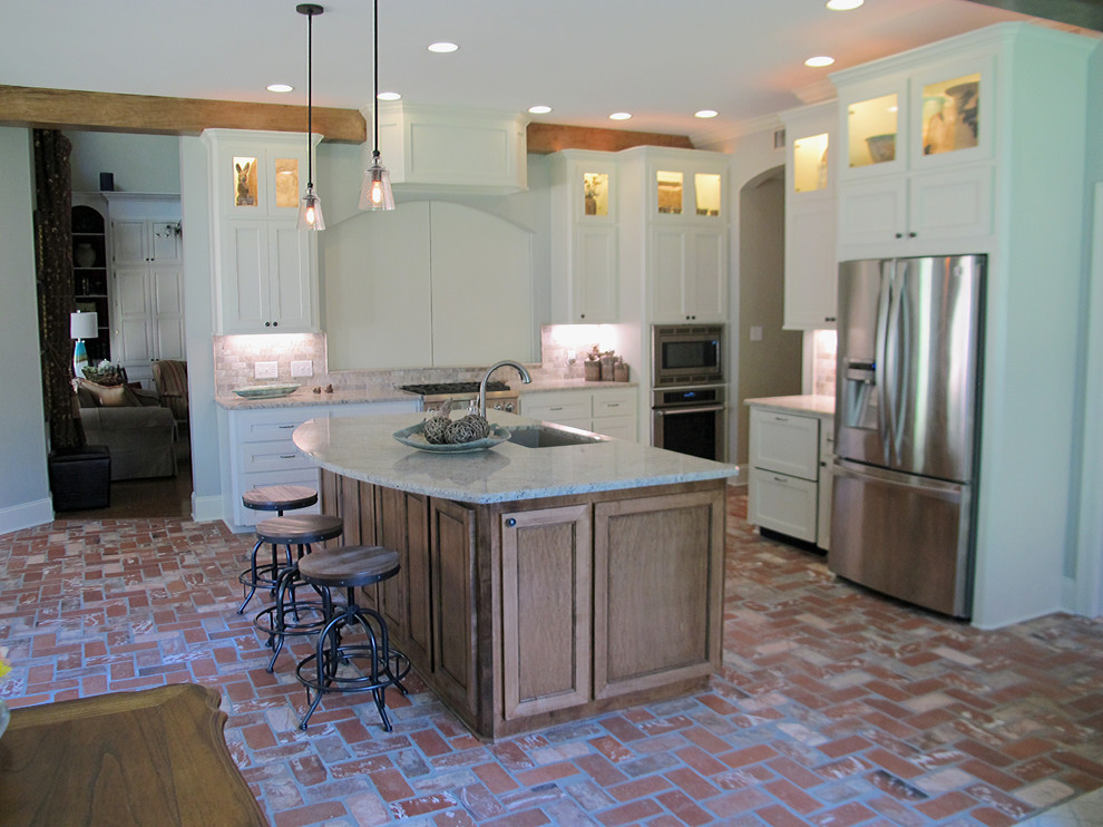 Inredning av ett klassiskt mellanstort kök, med en undermonterad diskho, luckor med infälld panel, vita skåp, granitbänkskiva, brunt stänkskydd, stänkskydd i stenkakel, rostfria vitvaror, tegelgolv och en köksö