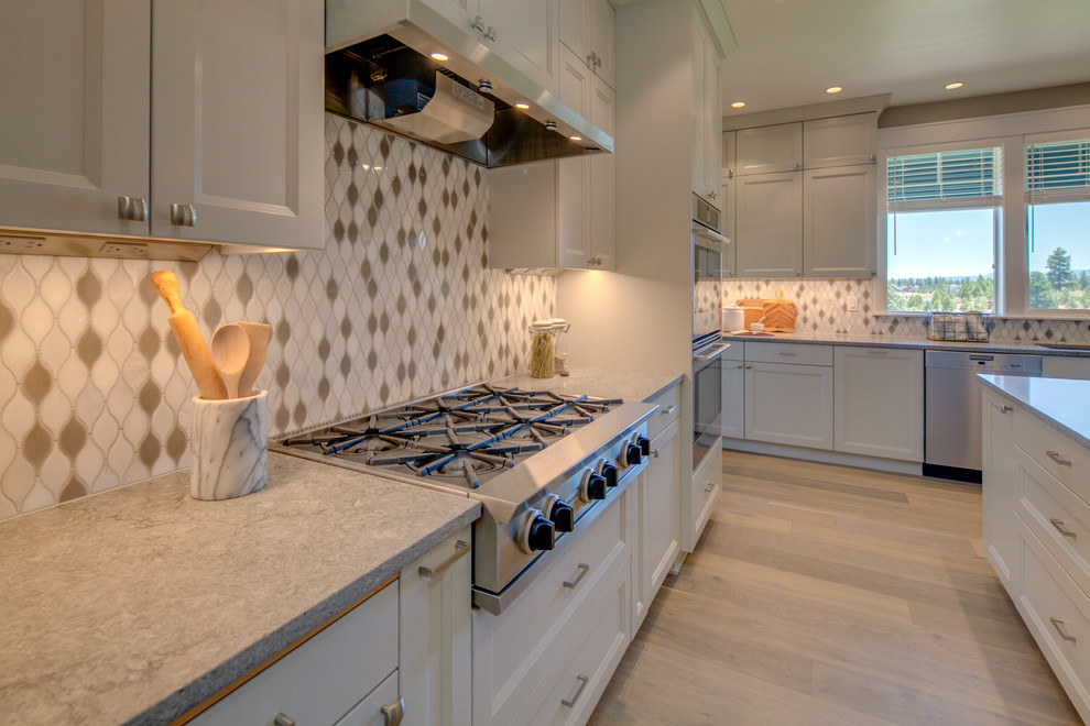 Idéer för att renovera ett mellanstort amerikanskt grå grått kök, med en undermonterad diskho, luckor med infälld panel, grå skåp, bänkskiva i kvarts, vitt stänkskydd, stänkskydd i keramik, rostfria vitvaror, mellanmörkt trägolv, en köksö och brunt golv