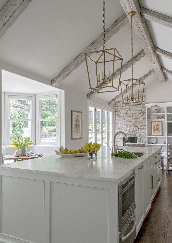 Exempel på ett stort klassiskt kök med öppen planlösning, med en undermonterad diskho, luckor med infälld panel, vita skåp, marmorbänkskiva, vitt stänkskydd, stänkskydd i sten, integrerade vitvaror, mellanmörkt trägolv, en köksö och brunt golv