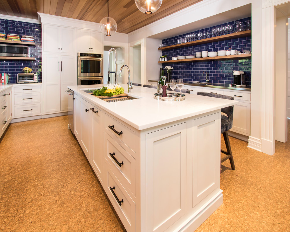 Large traditional u-shaped enclosed kitchen in New York with a submerged sink, shaker cabinets, grey cabinets, blue splashback, cement tile splashback, stainless steel appliances, cork flooring, an island, brown floors, white worktops and composite countertops.