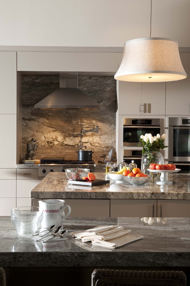 Eat-in kitchen - huge traditional eat-in kitchen idea in Orlando with stainless steel appliances, flat-panel cabinets, white cabinets, granite countertops, brown backsplash, an island and marble backsplash