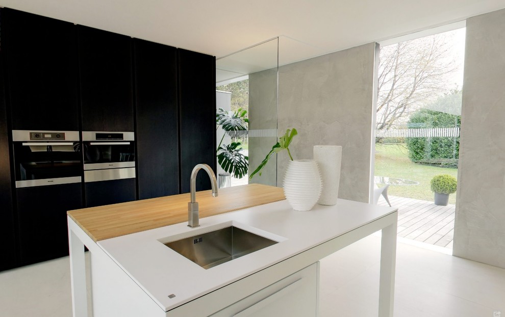 Photo of a contemporary kitchen/diner in London with a built-in sink, white appliances, an island and white floors.
