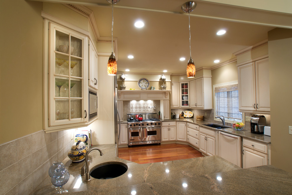 Eat-in kitchen - large traditional medium tone wood floor eat-in kitchen idea in New York with an undermount sink, white cabinets, granite countertops, ceramic backsplash, stainless steel appliances and raised-panel cabinets