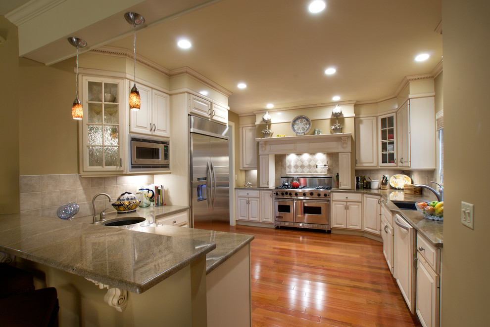 Large elegant medium tone wood floor eat-in kitchen photo in New York with an undermount sink, white cabinets, granite countertops, ceramic backsplash, stainless steel appliances and raised-panel cabinets