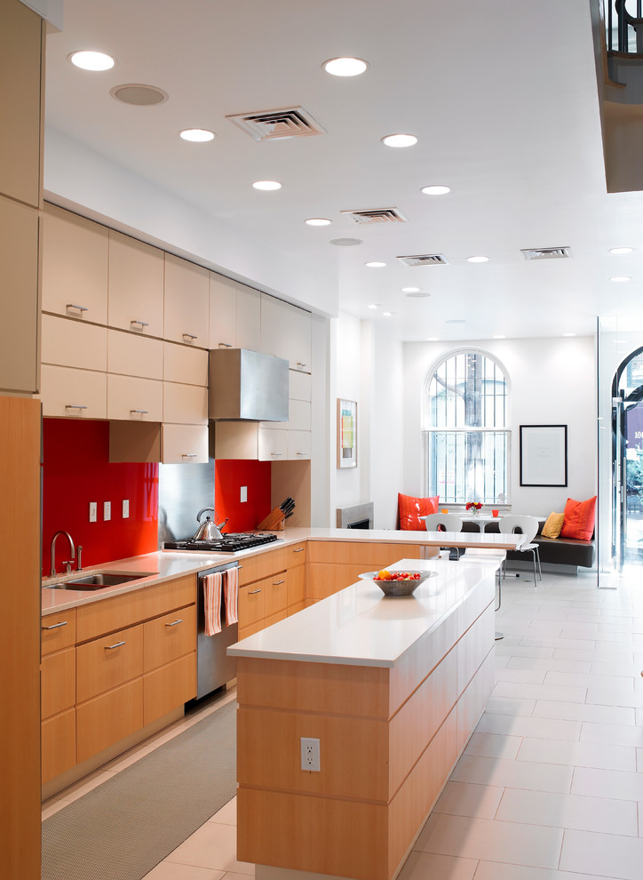 Источник вдохновения для домашнего уюта: угловая кухня в современном стиле с обеденным столом, плоскими фасадами, светлыми деревянными фасадами и красным фартуком