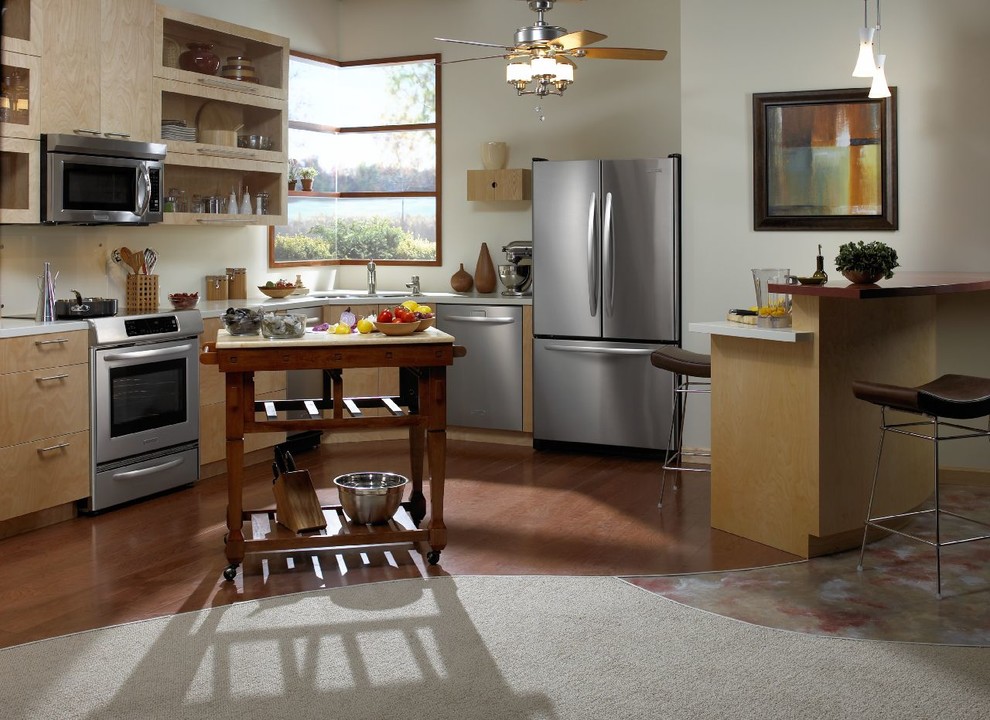 Esempio di una piccola cucina moderna con elettrodomestici in acciaio inossidabile e pavimento in legno massello medio