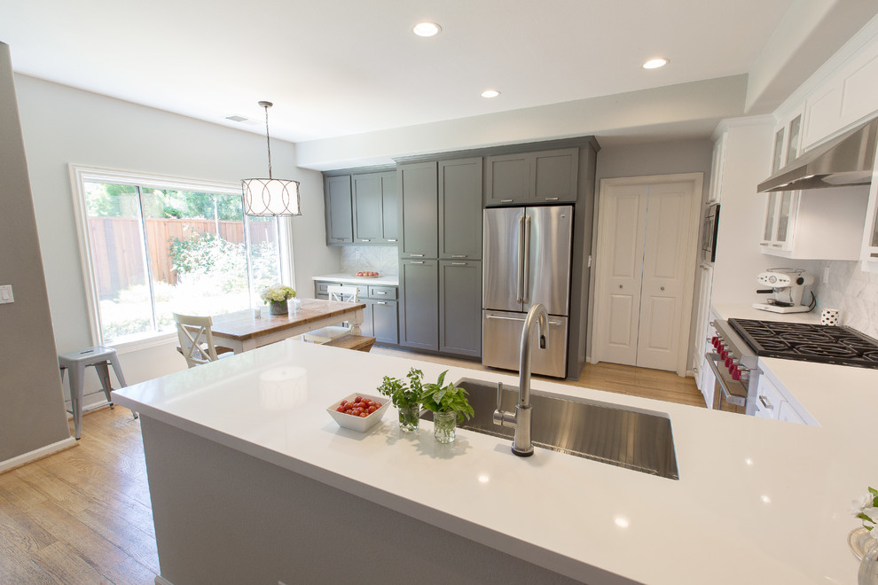 Example of a large kitchen design in Sacramento with an undermount sink, shaker cabinets, white cabinets, quartz countertops, white backsplash and stainless steel appliances