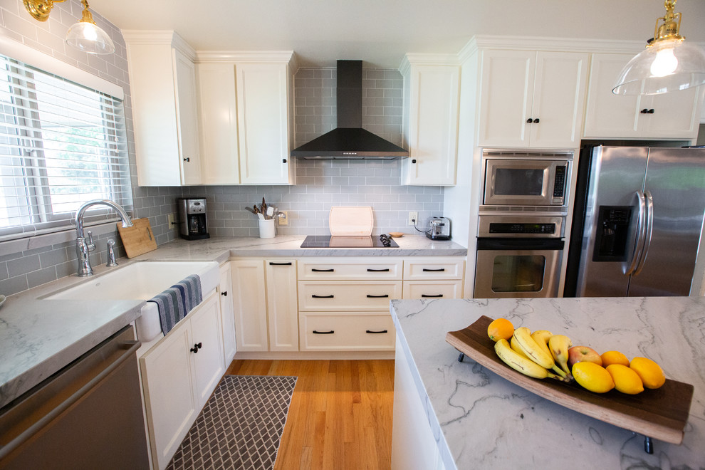 Bild på ett stort funkis grå grått kök, med en rustik diskho, vita skåp, bänkskiva i kvartsit, grått stänkskydd, stänkskydd i tunnelbanekakel, rostfria vitvaror och en köksö