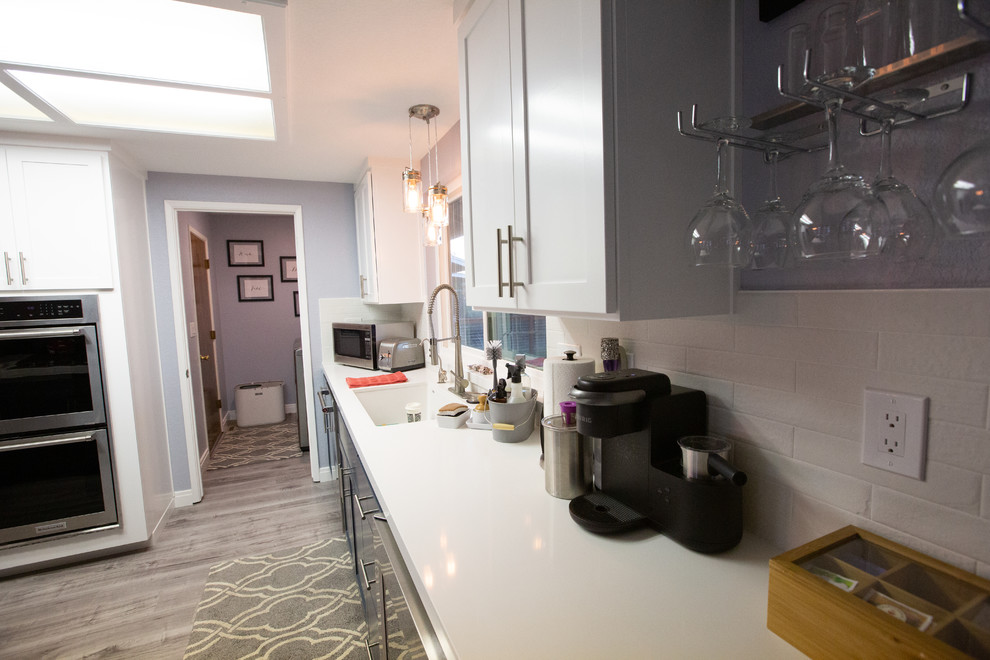 Immagine di una grande cucina moderna con lavello sottopiano, ante grigie, top in quarzo composito, paraspruzzi bianco, paraspruzzi in gres porcellanato, elettrodomestici in acciaio inossidabile e top grigio