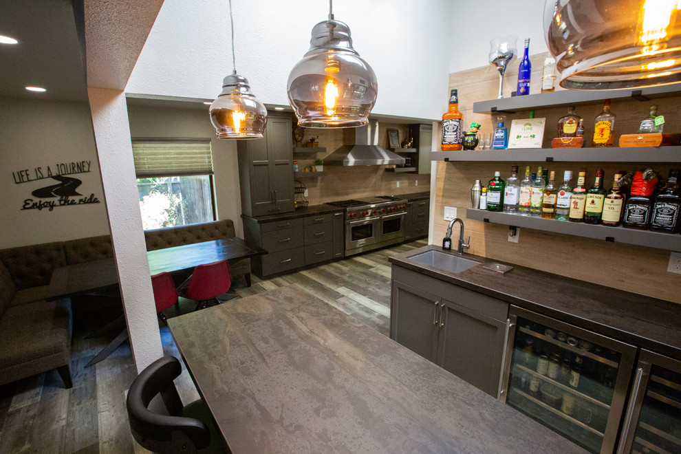 Foto på ett funkis grå kök, med en undermonterad diskho, grå skåp, brunt stänkskydd, rostfria vitvaror och brunt golv
