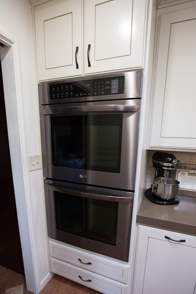 Foto de cocina moderna con fregadero bajoencimera, puertas de armario blancas, encimera de piedra caliza, salpicadero beige y electrodomésticos de acero inoxidable