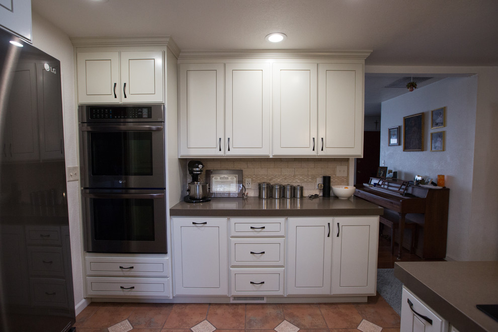 Exemple d'une cuisine moderne avec un évier encastré, des portes de placard blanches, un plan de travail en calcaire, une crédence beige et un électroménager en acier inoxydable.