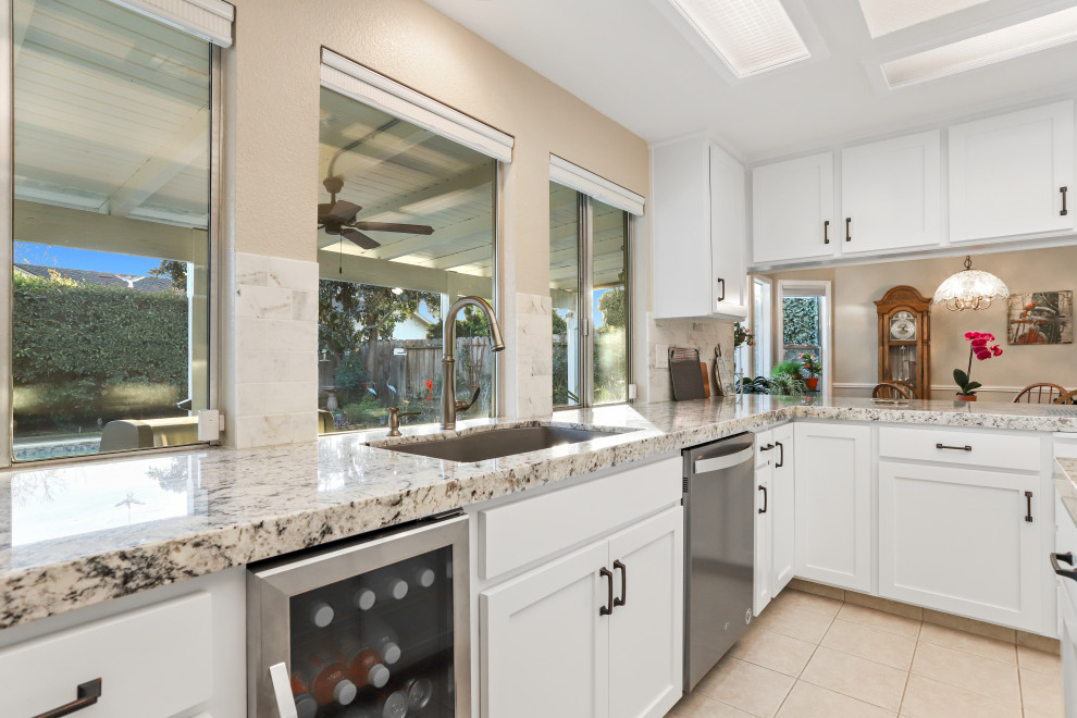 Foto på ett funkis flerfärgad kök, med en dubbel diskho, vita skåp, granitbänkskiva, flerfärgad stänkskydd, stänkskydd i marmor, rostfria vitvaror och en köksö