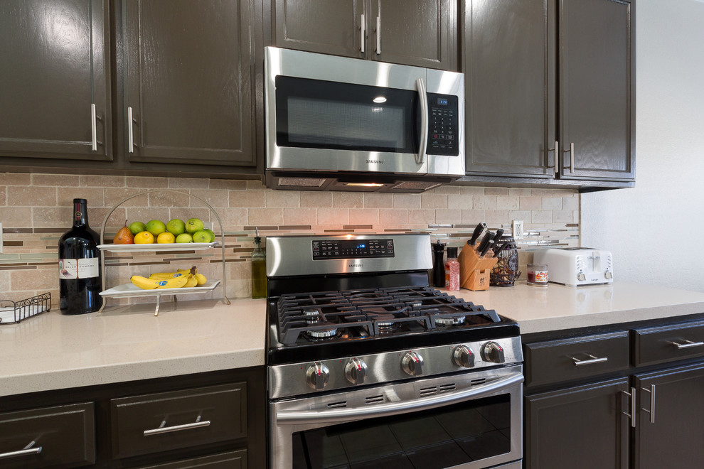 Immagine di un cucina con isola centrale minimalista con lavello sottopiano, ante marroni, top in quarzo composito e elettrodomestici in acciaio inossidabile