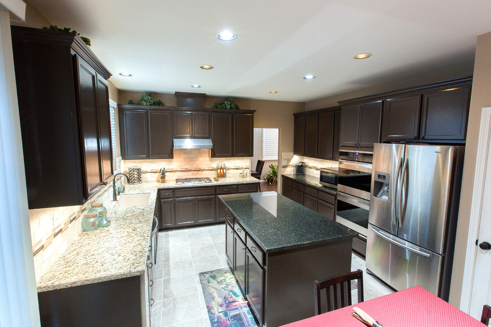 Kitchen photo in Sacramento with a single-bowl sink, brown cabinets, granite countertops, beige backsplash, stainless steel appliances and an island