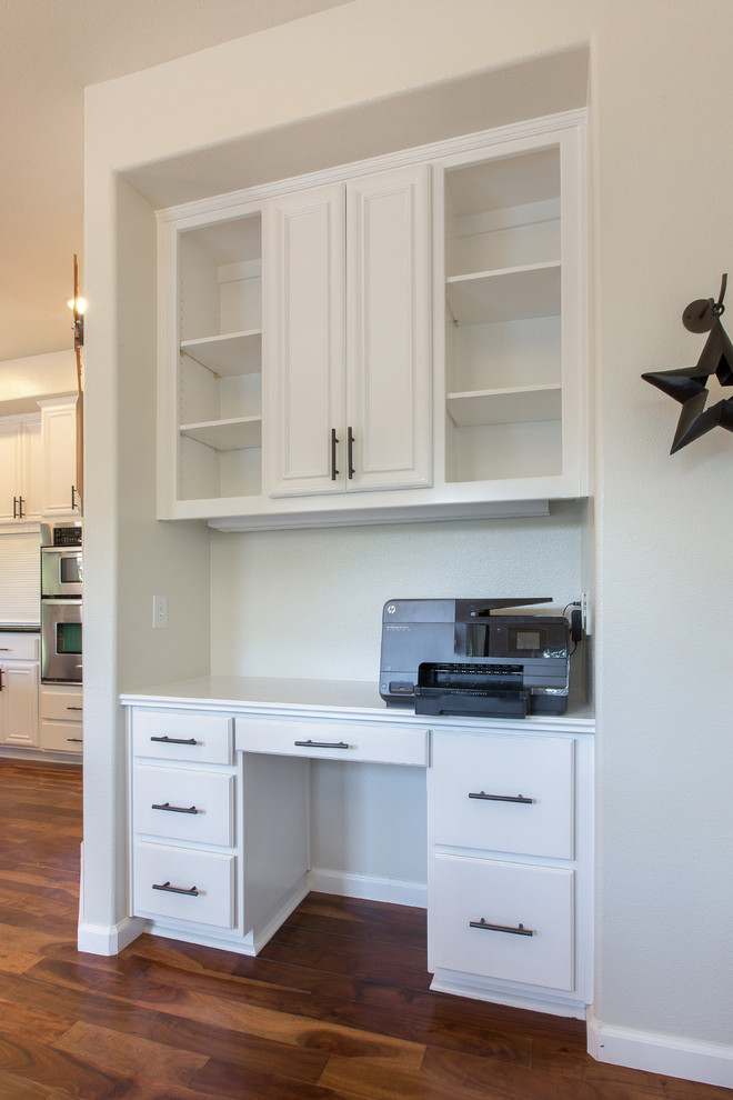 Cette image montre une cuisine minimaliste avec des portes de placard blanches et îlot.