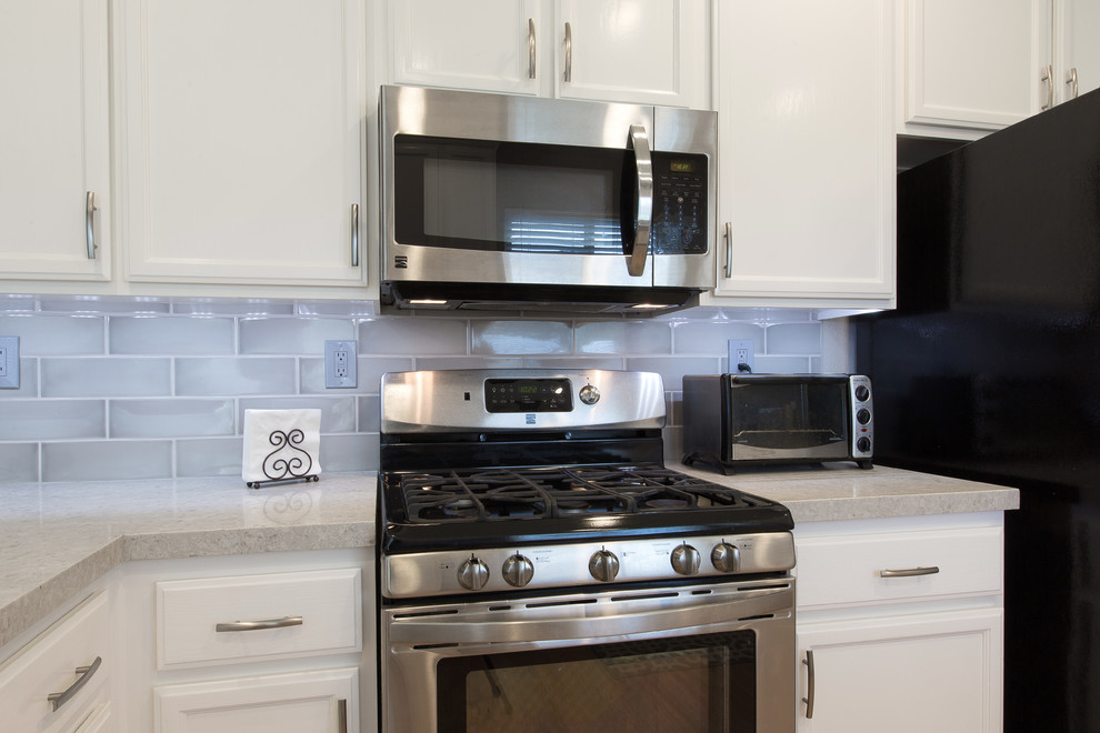 Moderne Küche in L-Form mit Landhausspüle, weißen Schränken, Quarzwerkstein-Arbeitsplatte, Küchenrückwand in Grau, Rückwand aus Keramikfliesen und Küchengeräten aus Edelstahl in Sacramento
