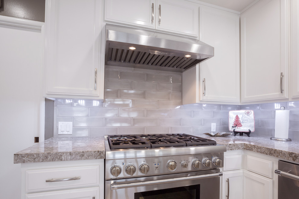 Immagine di una cucina ad U minimalista con lavello sottopiano, ante bianche, top in quarzo composito, paraspruzzi grigio, paraspruzzi con piastrelle in ceramica e elettrodomestici in acciaio inossidabile