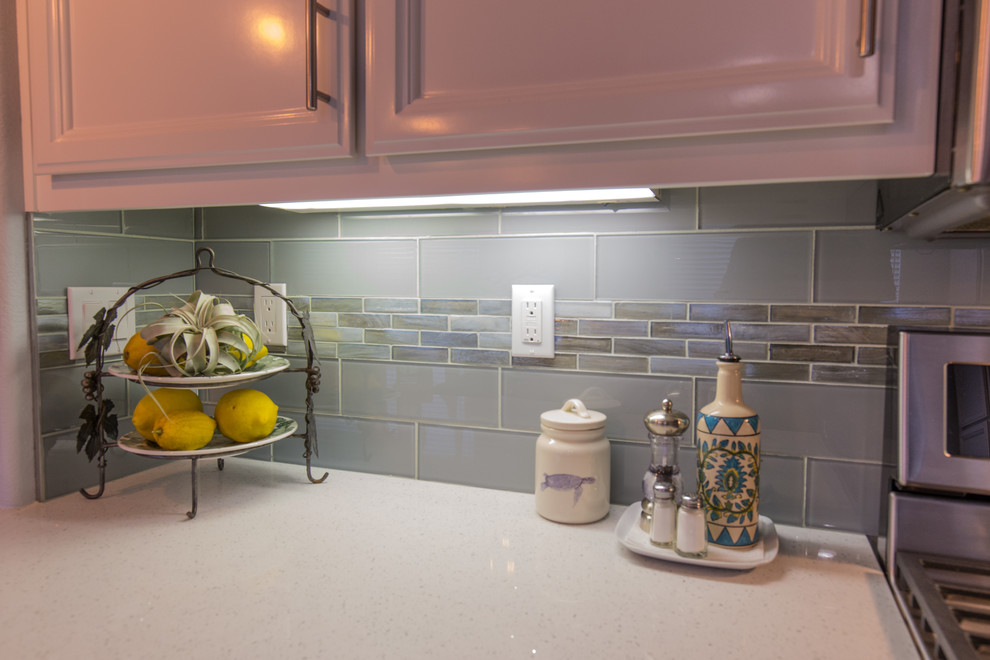 Exemple d'une cuisine moderne avec un évier encastré, des portes de placard grises, un plan de travail en quartz modifié, une crédence verte, une crédence en carreau de verre, un électroménager en acier inoxydable et une péninsule.