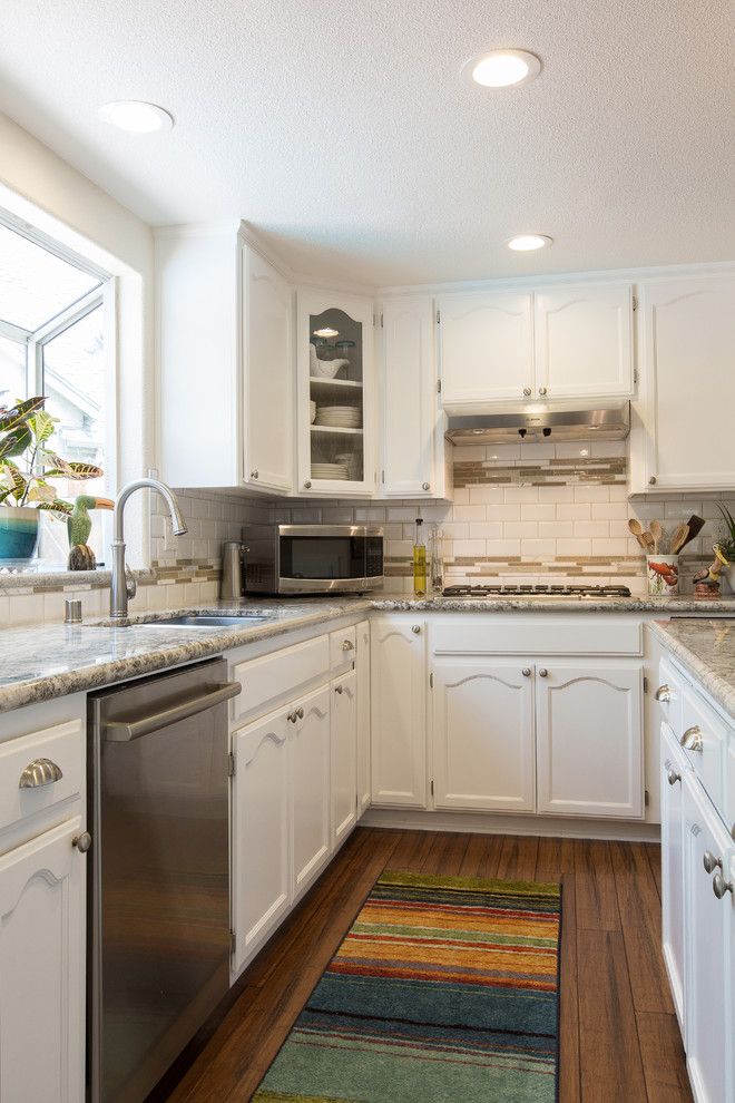 Inspiration for a modern kitchen remodel in Sacramento with an undermount sink, white cabinets, granite countertops, white backsplash, ceramic backsplash, stainless steel appliances and an island