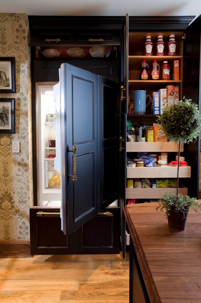 ニューヨークにある広いトラディショナルスタイルのおしゃれなキッチン (落し込みパネル扉のキャビネット、黒いキャビネット、木材カウンター、黒い調理設備、無垢フローリング、ベージュキッチンパネル) の写真