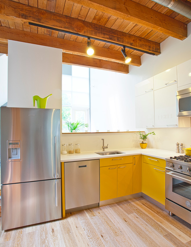 Example of a mountain style l-shaped kitchen design in Other with stainless steel appliances, a single-bowl sink, flat-panel cabinets and yellow cabinets