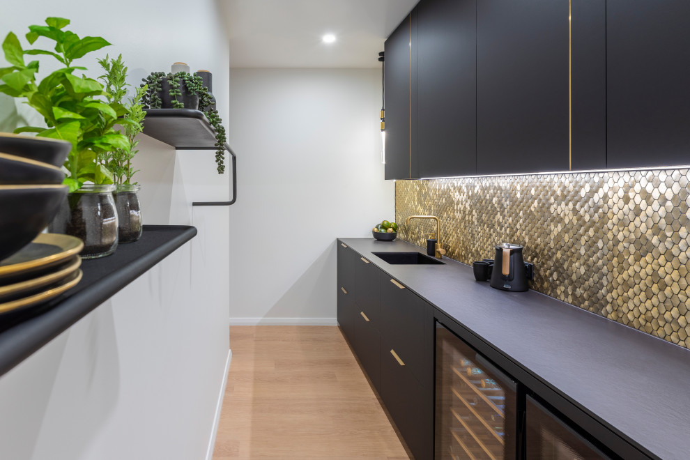 Immagine di una grande cucina minimal con lavello sottopiano, ante nere, paraspruzzi con piastrelle a mosaico, elettrodomestici neri, pavimento in laminato e top nero