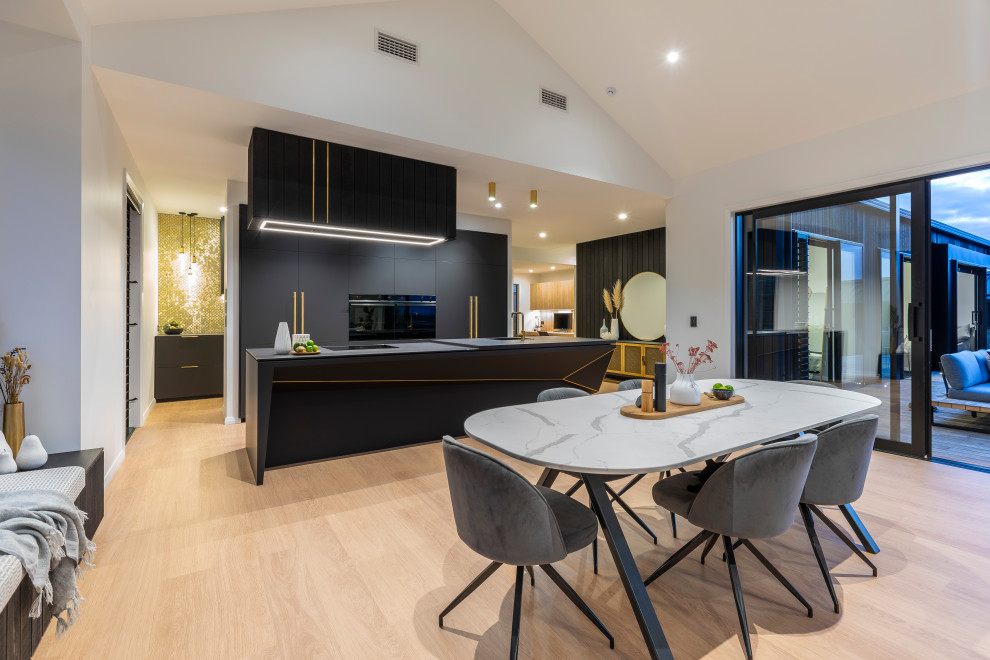 Large contemporary galley open plan kitchen in Auckland with a submerged sink, black cabinets, mosaic tiled splashback, black appliances, laminate floors, an island and black worktops.