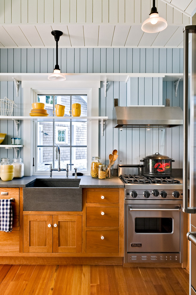 This is an example of a nautical kitchen in Portland Maine with stainless steel appliances, a belfast sink, shaker cabinets, medium wood cabinets and multi-coloured splashback.