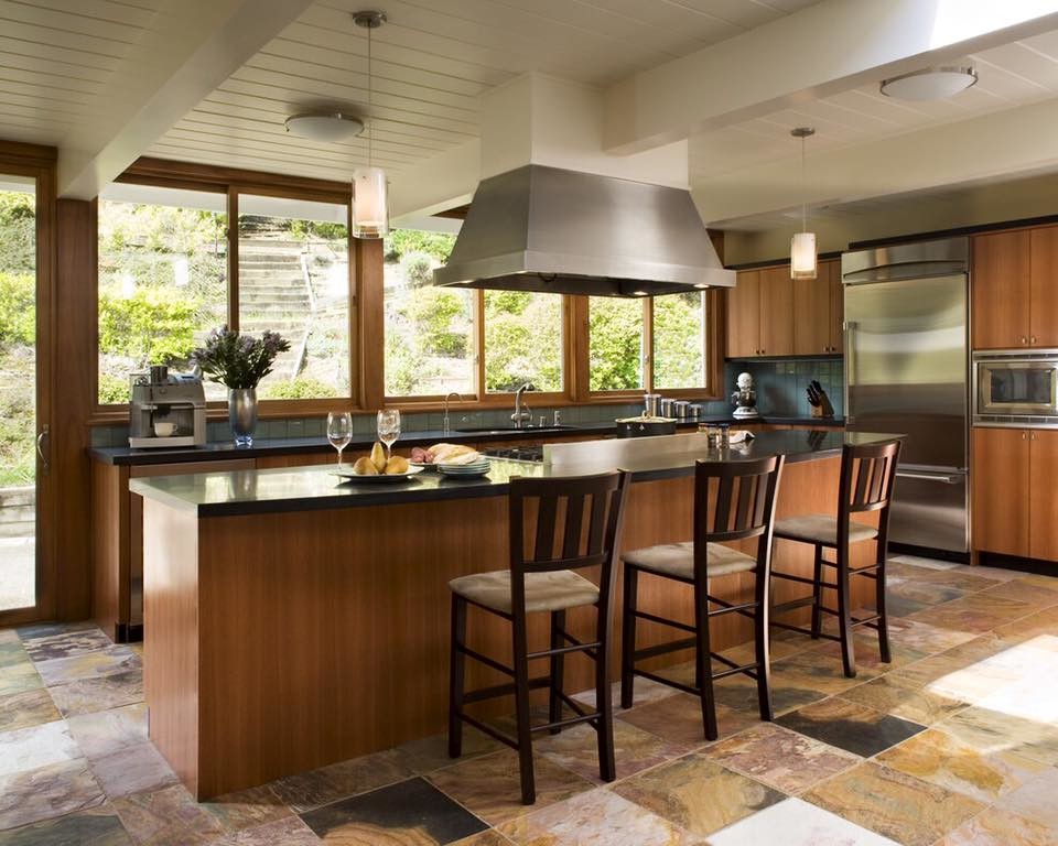 Eat-in kitchen - mid-sized contemporary l-shaped slate floor eat-in kitchen idea in Milwaukee with an undermount sink, flat-panel cabinets, medium tone wood cabinets, solid surface countertops, blue backsplash, ceramic backsplash, stainless steel appliances and an island