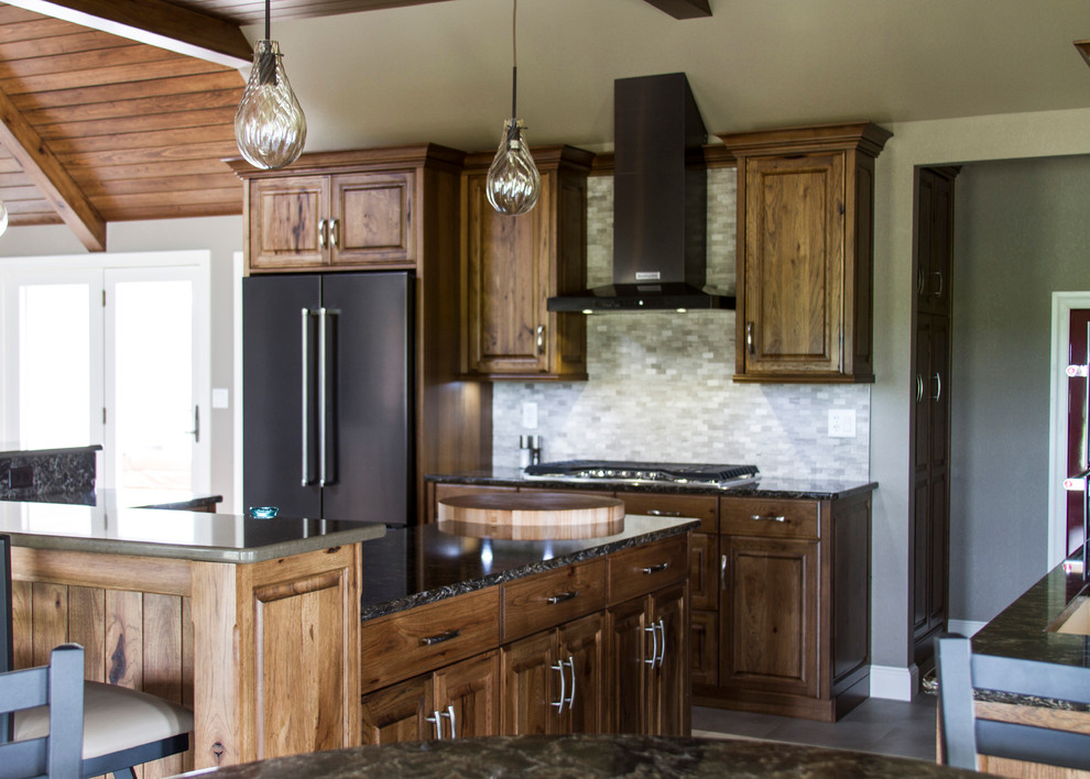 Example of a large mountain style l-shaped porcelain tile and gray floor eat-in kitchen design in Columbus with an undermount sink, raised-panel cabinets, medium tone wood cabinets, granite countertops, multicolored backsplash, stainless steel appliances, an island and stone tile backsplash