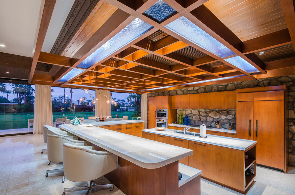 Contemporary u-shaped kitchen in Los Angeles with flat-panel cabinets, medium wood cabinets, integrated appliances and multiple islands.