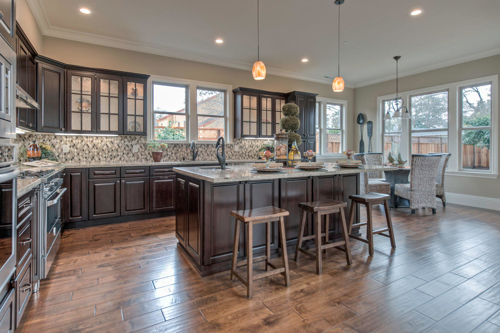 Mid-sized arts and crafts l-shaped medium tone wood floor and brown floor open concept kitchen photo in San Francisco with a double-bowl sink, dark wood cabinets, granite countertops, stainless steel appliances, an island, raised-panel cabinets, multicolored backsplash and mosaic tile backsplash